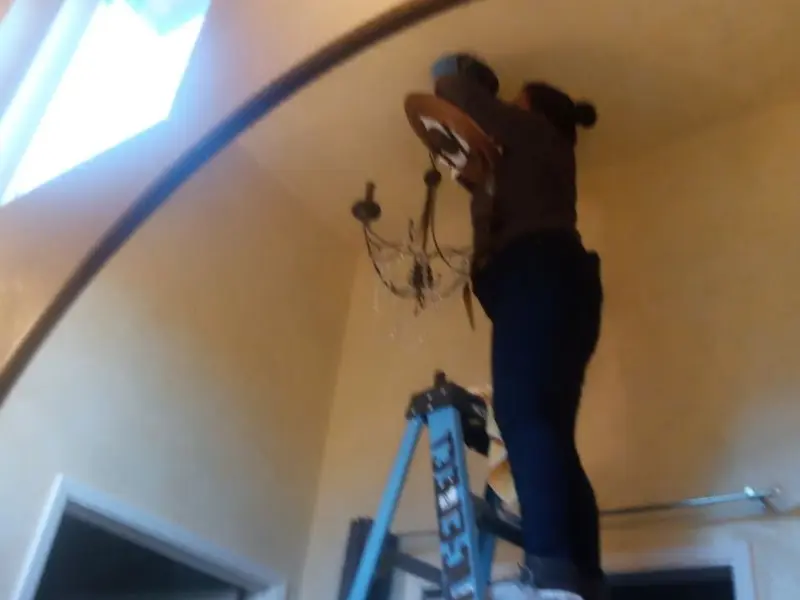 Electrician installing a chandelier in a Sullivan residence
